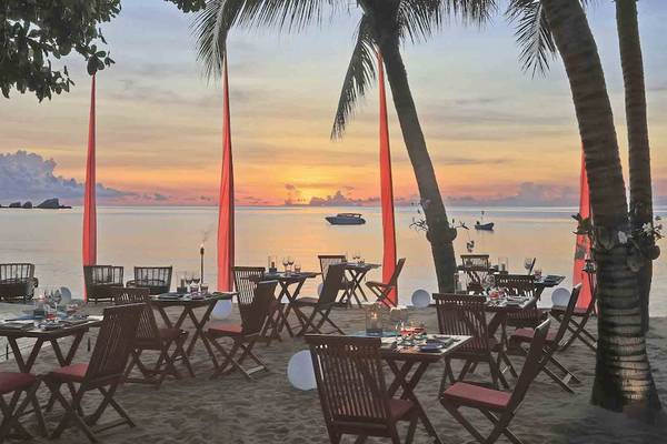 Restaurant am Strand bei Sonnenuntergang mit Blick auf das Meer und roten Fahnen.