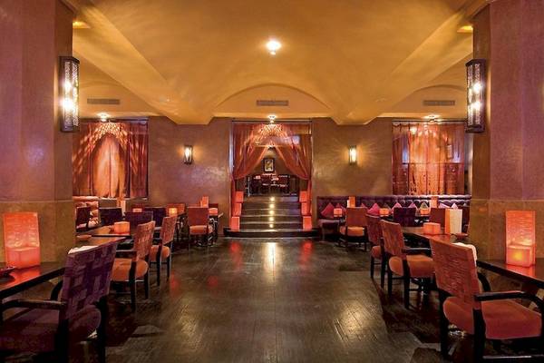 Innenansicht des Atlas Medina & Spa Restaurants mit dunklem Holzboden und roten Vorhängen.