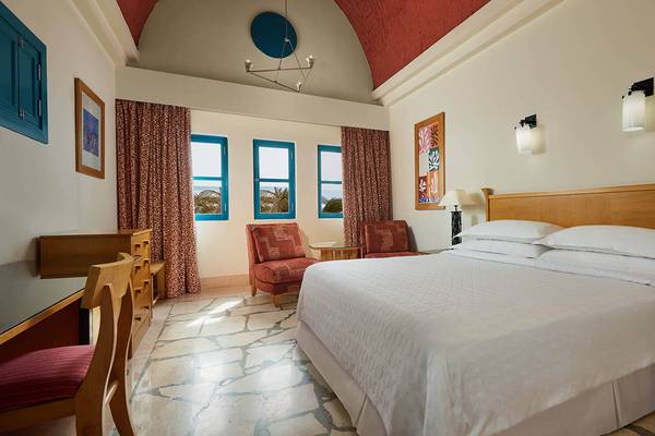 Innenansicht des Schlafzimmers im Sheraton Miramar Resort El Gouna mit einem großen Bett und Fenstern