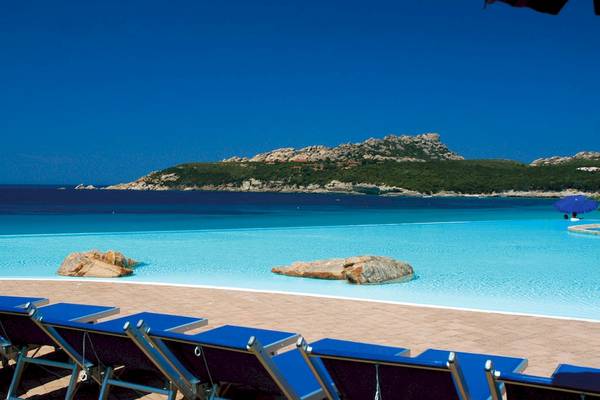 Pool im Colonna Grand Hotel Capo Testa mit Blick auf das Meer und eine Insel.