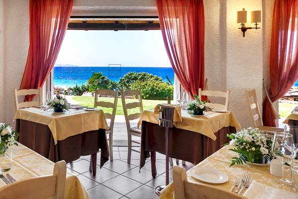 Speisesaal mit Meerblick im Colonna Grand Hotel Capo Testa mit roten Vorhängen und gelben Tischdecken.
