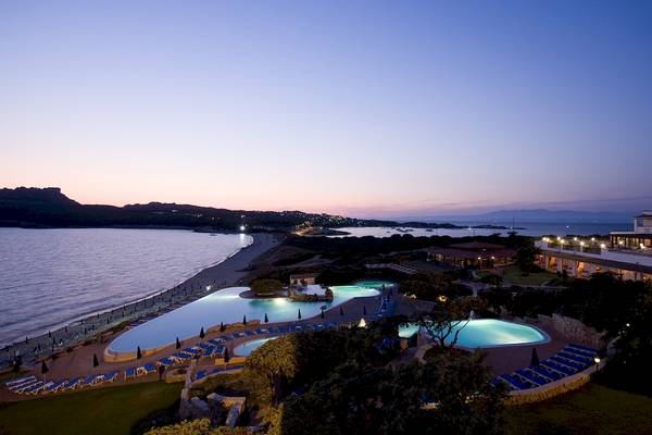 Abendlicher Blick auf Colonna Grand Hotel Capo Testa mit Swimmingpools und Blick auf den Strand