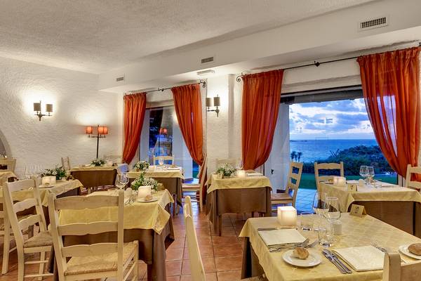 Restaurant-Innenbereich des Colonna Grand Hotel Capo Testa mit Blick auf das Meer.