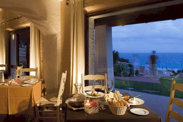 Innenansicht des Essbereichs des Colonna Grand Hotel Capo Testa mit Blick auf das Meer.