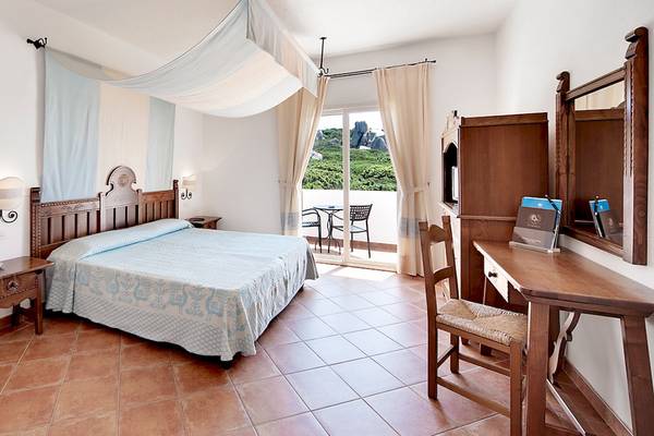 Doppelbett-Zimmer mit Balkon im Colonna Grand Hotel Capo Testa mit Aussicht auf eine Terrasse.