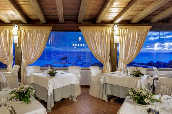 Innenansicht des Restaurants im Colonna Grand Hotel Capo Testa mit Blick auf das Meer.