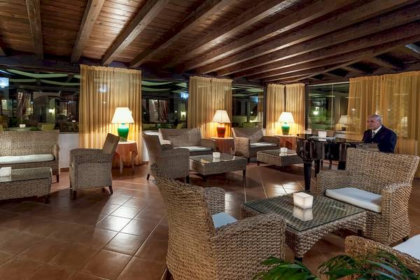 Innenansicht der Lobby des Colonna Grand Hotel Capo Testa mit Möbeln und Lampen