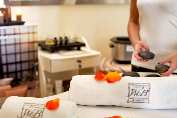 Spa-Behandlung im Colonna Grand Hotel Capo Testa mit weißen Handtüchern und Rosenblättern.