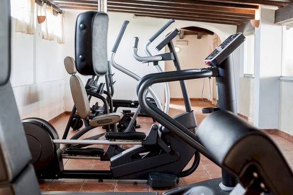 Fitnessbereich im Colonna Grand Hotel Capo Testa mit mehreren Geräten wie Laufbändern und Rudergeräten.