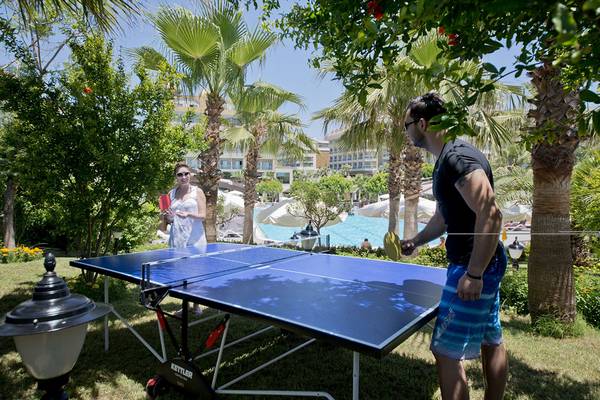 Ein Paar spielt Tischtennis im Garten des Aydinbey Kings Palace & Spa Hotels.