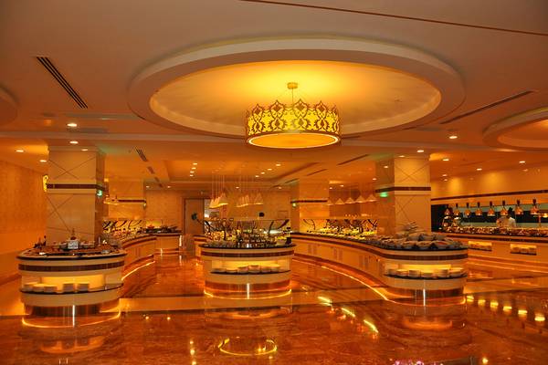 Innenansicht des Restaurants im Aydinbey Kings Palace & Spa mit vielen Essensstationen und einer großen Kronleuchter.