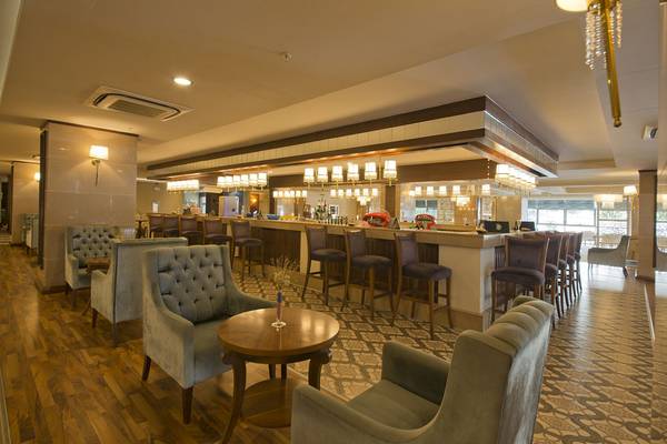 Innenansicht der Bar im Aydinbey Kings Palace & Spa Hotel mit gepolsterten Stühlen und einer Theke.