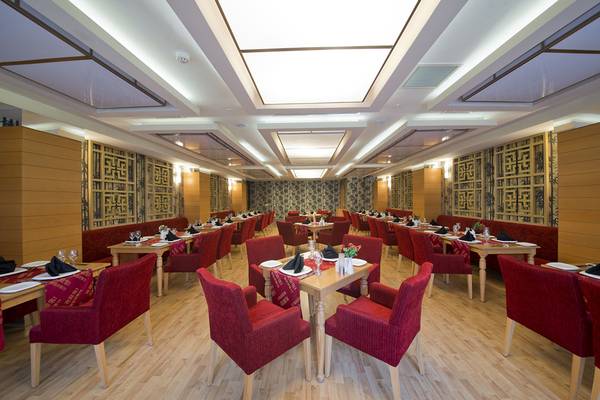 Innenbereich des Restaurants im Aydinbey Kings Palace & Spa Hotel mit roten Stühlen und Tischen.