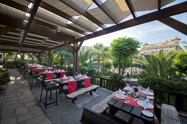 Außenbereich des Aydinbey Kings Palace & Spa Restaurants mit gedeckten Tischen und Pflanzen.