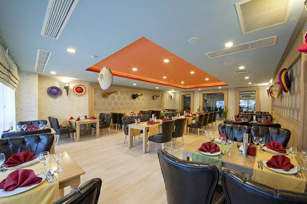 Innenbereich des Restaurants im Aydinbey Kings Palace & Spa Hotel mit gedeckten Tischen und Stühlen.