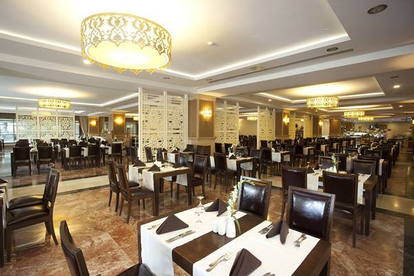 Restaurantbereich im Aydinbey Kings Palace Hotel mit vielen gedeckten Tischen und Stühlen.