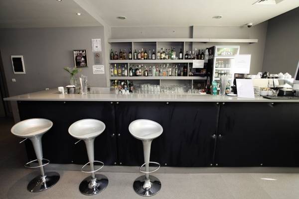 Die Bar im Gladiola Star Hotel mit Barhockern und einer Theke voller Getränke.