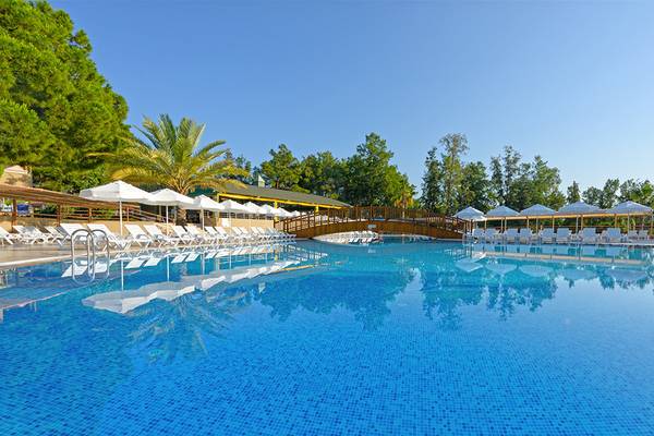 Außenpool des Club Hotel Sidelya mit Liegestühlen, Sonnenschirmen und einer Brücke.