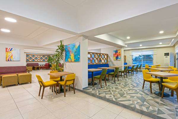 Innenbereich des Club Hotel Sidelya mit gelben Stühlen, blauen Sofas und bunten Gemälden an den Wänden.