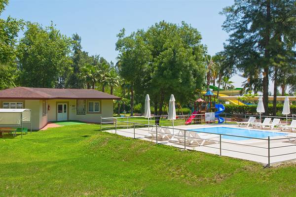 Außenbereich des Club Hotel Sidelya mit Pool, Liegestühlen und Spielgeräten.