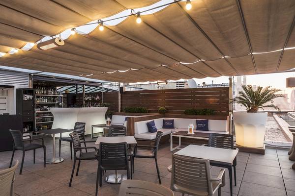Dachterrasse des Gran Hotel Havana Barcelona mit Tischen, Stühlen und einer Bar.