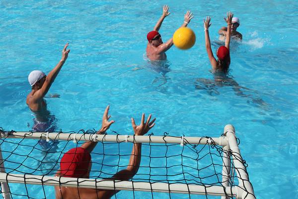 Spieler spielen Wasserball im Schwimmbecken mit Netztor.