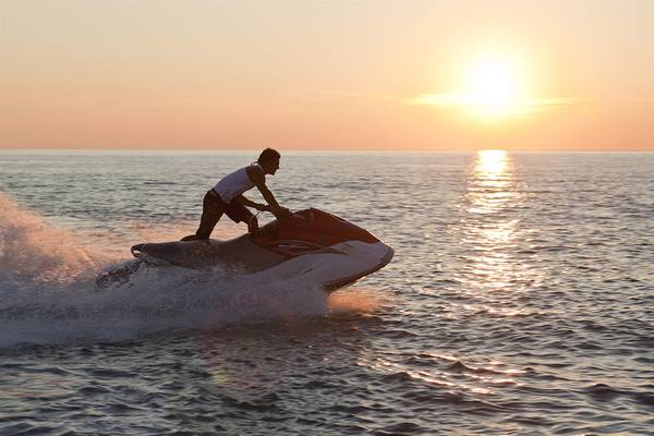 Mann auf Jet Ski bei Sonnenuntergang auf dem Meer