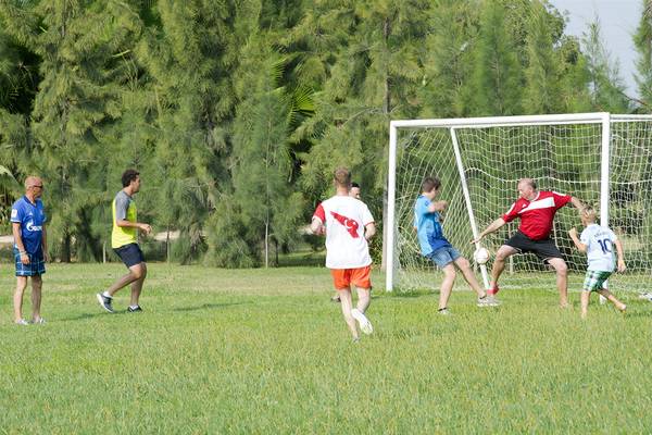Gruppe von Menschen, die auf einer Rasenfläche Fußball spielen, Club Hotel Sidelya im Hintergrund.