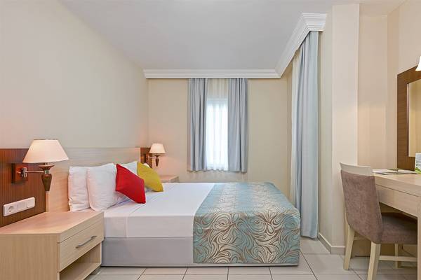 Innenansicht eines geschmackvoll eingerichteten Zimmers im Club Hotel Sidelya mit einem Doppelbett, Nachttischen und Schreibtisch.