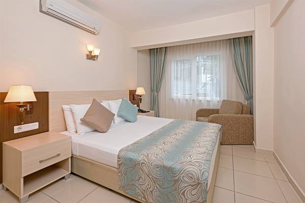 Innenansicht eines Doppelzimmers im Club Hotel Sidelya mit einem Bett, Sessel und Klimaanlage.