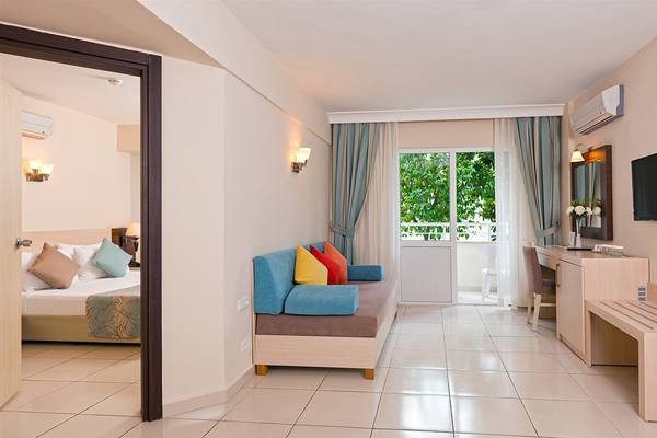 Innenansicht eines Hotelzimmers mit Bett, Sofa, Schreibtisch und Klimaanlage.