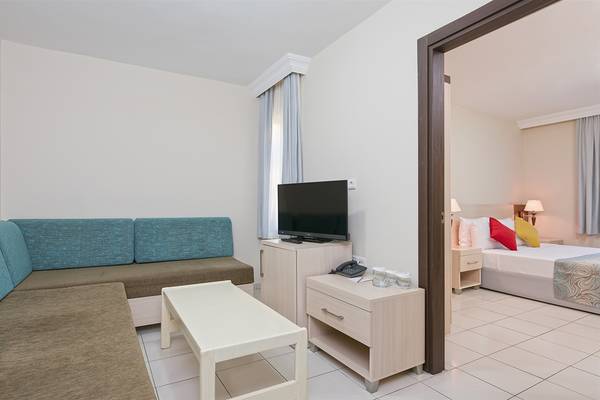 Zimmer im Club Hotel Sidelya mit Wohnzimmerbereich, Sofa, Tisch, Fernseher und Schlafzimmer mit Bett.
