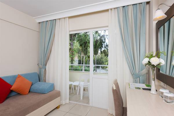 Ein Hotelzimmer mit einem Sofa, einem Balkon und einer Aussicht auf Bäume und Gebäude.