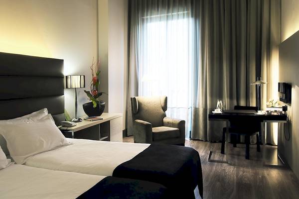 Doppelzimmer im Gran Hotel Havana Barcelona mit zwei Betten, Schreibtisch und Stuhl.