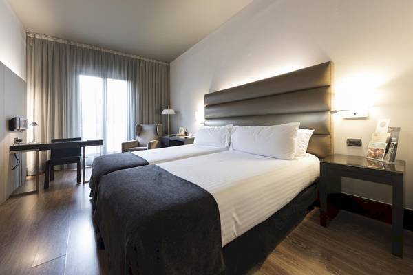 Doppelzimmer im Gran Hotel Havana Barcelona mit zwei Betten, Schreibtisch und Fenstern.