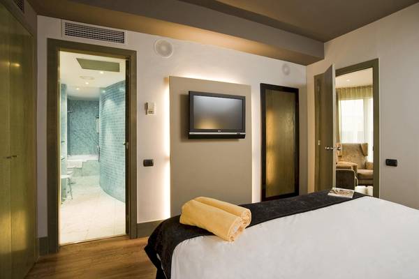 Hotelzimmer im Gran Hotel Havana Barcelona mit Fernseher, offenen Türen und Badezimmer.