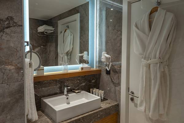 Badezimmer im Baia Lara Hotel mit Waschbecken, Spiegel und Handtüchern.