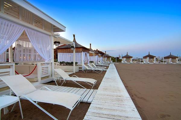 Außenbereich des Baia Lara Hotels mit weißen Sonnenliegen und Pavillons am Strand