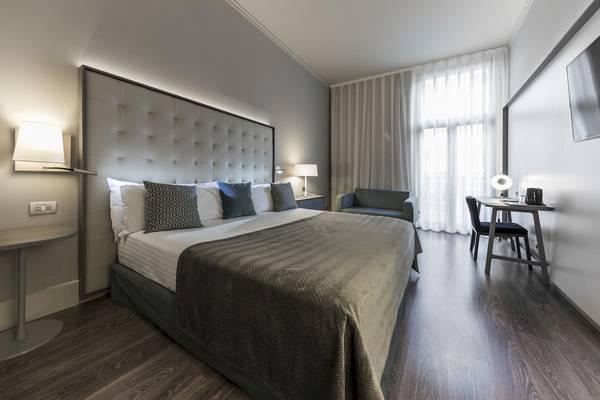 Schlafzimmer im Gran Hotel Havana Barcelona mit Bett, Nachttischen und Schreibtisch.