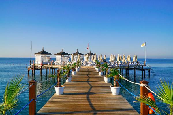 Anlegepier des Baia Lara Hotels mit Strandschirmen und Palmen an einem sonnigen Tag