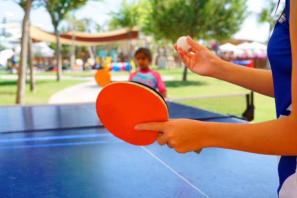 Eine Person spielt Tischtennis im Freien im Baia Lara Hotel, während eine andere Person den Ball hält.