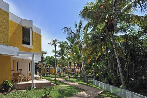 Außenansicht des Sol Palmeras Hotels mit gelben Gebäuden und Palmen.