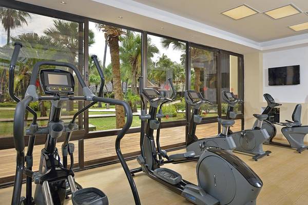 Fitnessstudio im Sol Palmeras Hotel mit Geräten und einem Mann, der etwas trägt.