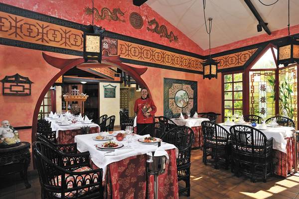Innenansicht des Sol Palmeras Restaurants mit asiatischem Dekor und einem Mitarbeiter, der die Tische bedient.