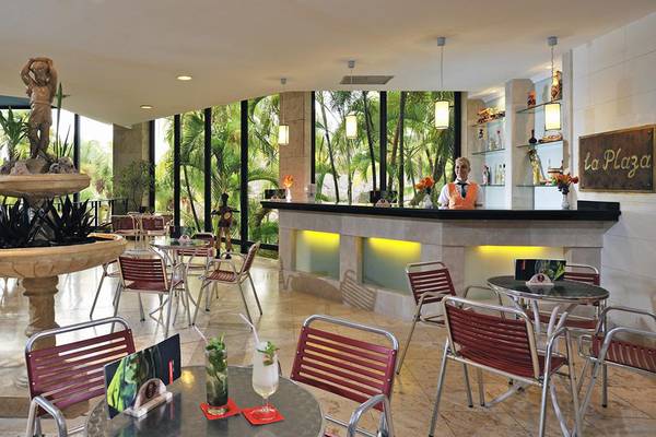 Innenansicht der Lobby-Bar des Sol Palmeras Hotels mit Brunnen, Tischen, Stühlen und einer Barfrau.
