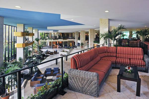 Lobby des Sol Palmeras Hotels mit roten Sofas, Tischen und Pflanzen.