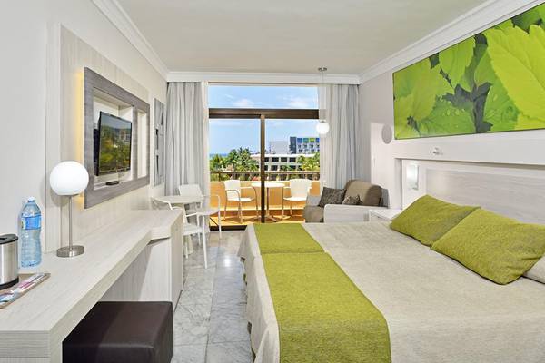 Hotelzimmer im Sol Palmeras mit zwei Betten, Schreibtisch, Fernseher und Balkon mit Meerblick.