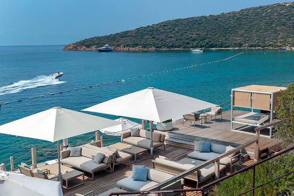 Kempinski Hotel Barbaros Bay mit Terrasse, Sofas, Sonnenschirmen und Blick aufs Meer.