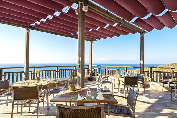 Außenterrasse des Kempinski Hotel Barbaros Bay mit Tischen und Stühlen, Meerblick und Sonnenschutz.