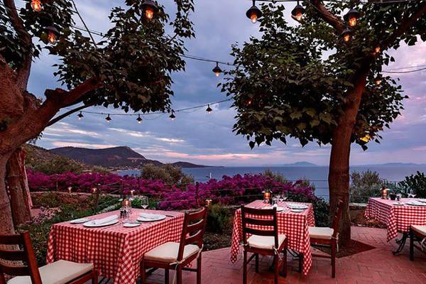 Terrasse des Kempinski Hotel Barbaros Bay in Bodrum bei Sonnenuntergang mit Blick auf das Meer.